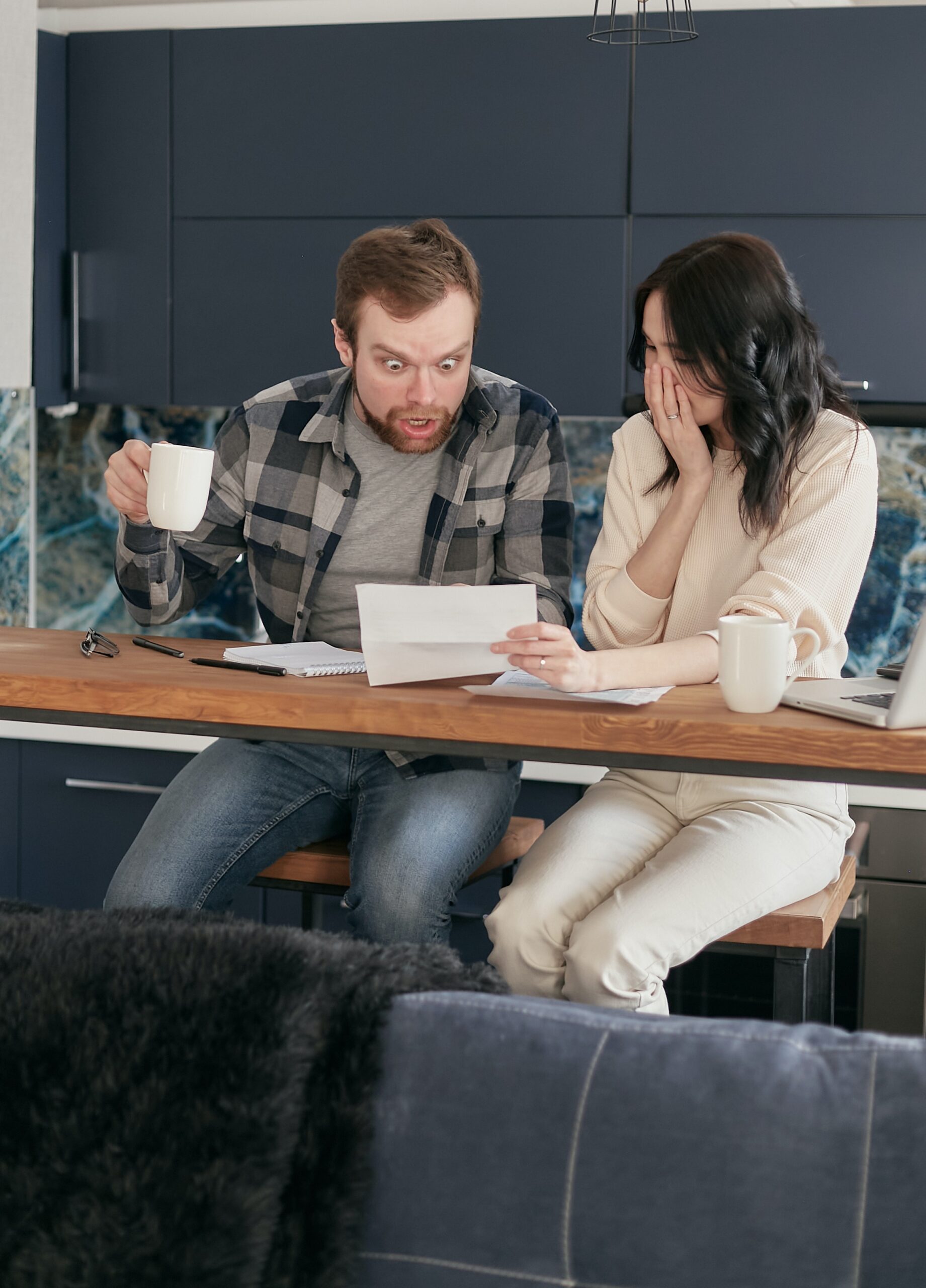 A man and a woman looking at a letter and appearing to be horrified.