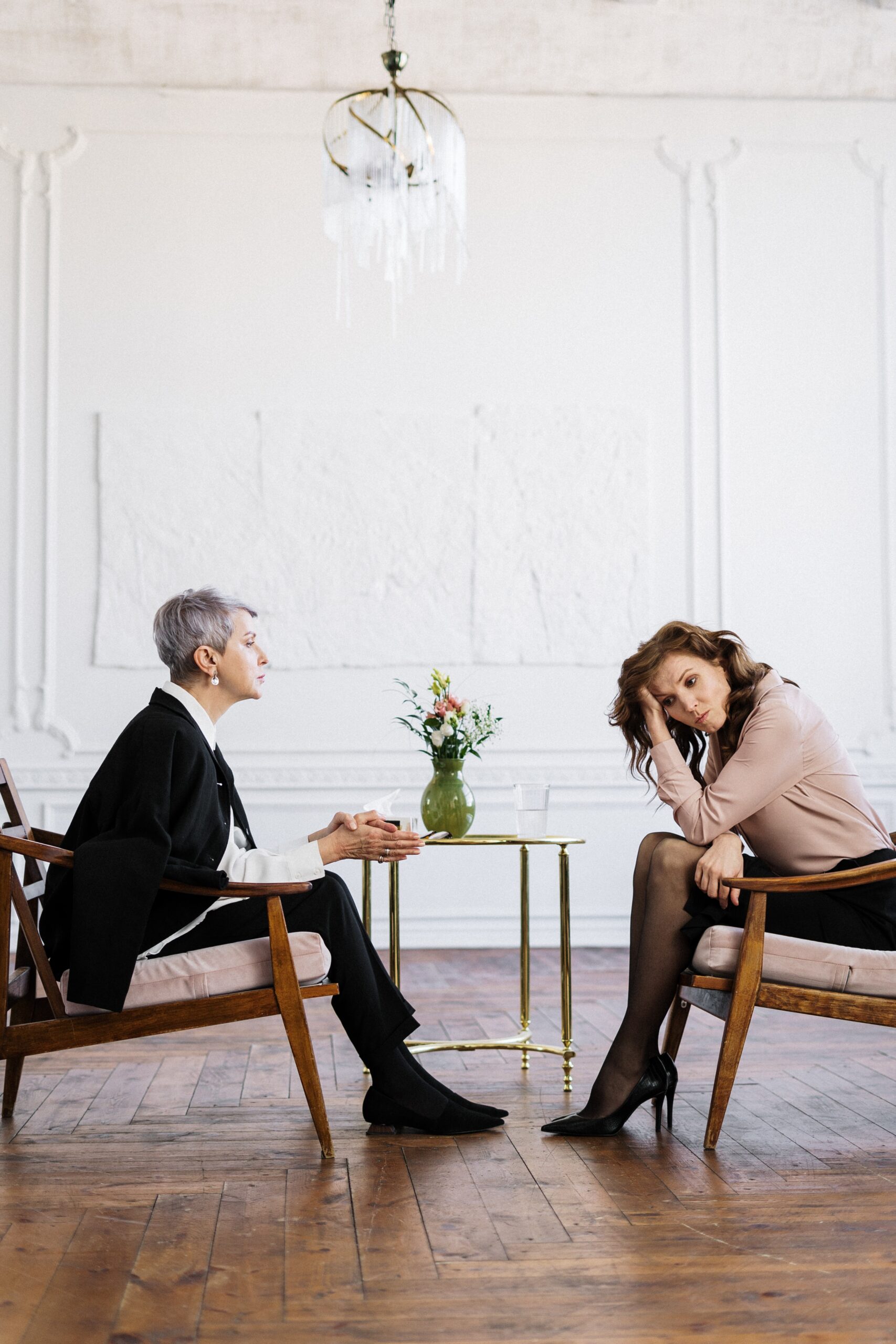 An older professional woman speaking to a younger woman who appears to be frustrated with what she is being told.