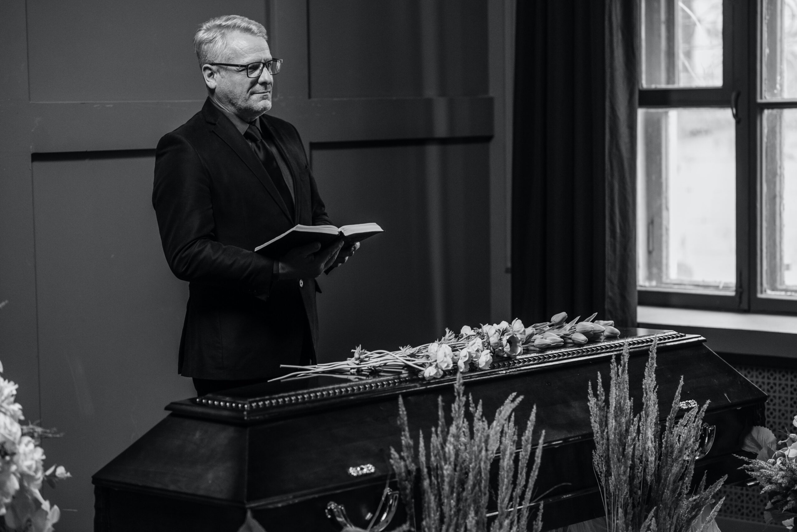 Officiant standing over coffin and holding a book.