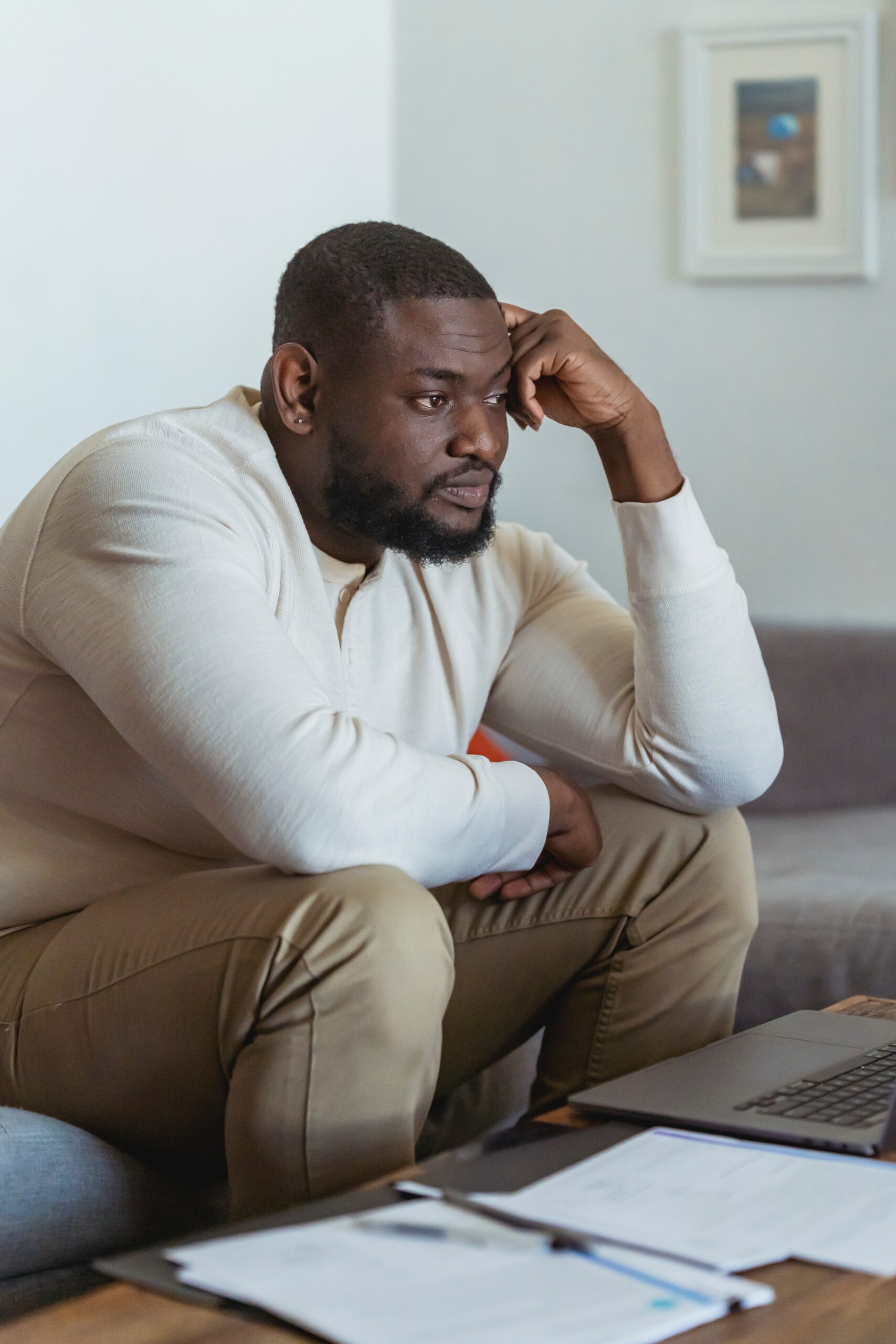 Man sitting hunched over and looking worried.