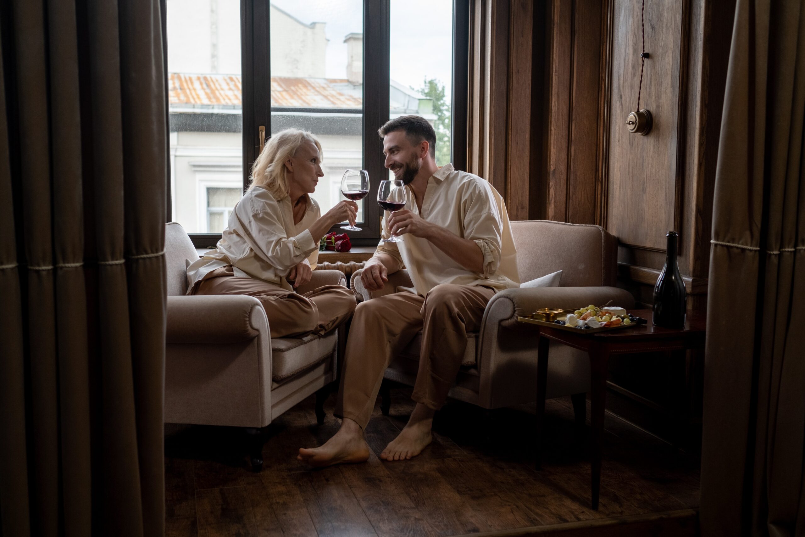 An older woman and younger man sitting together and drinking wine.