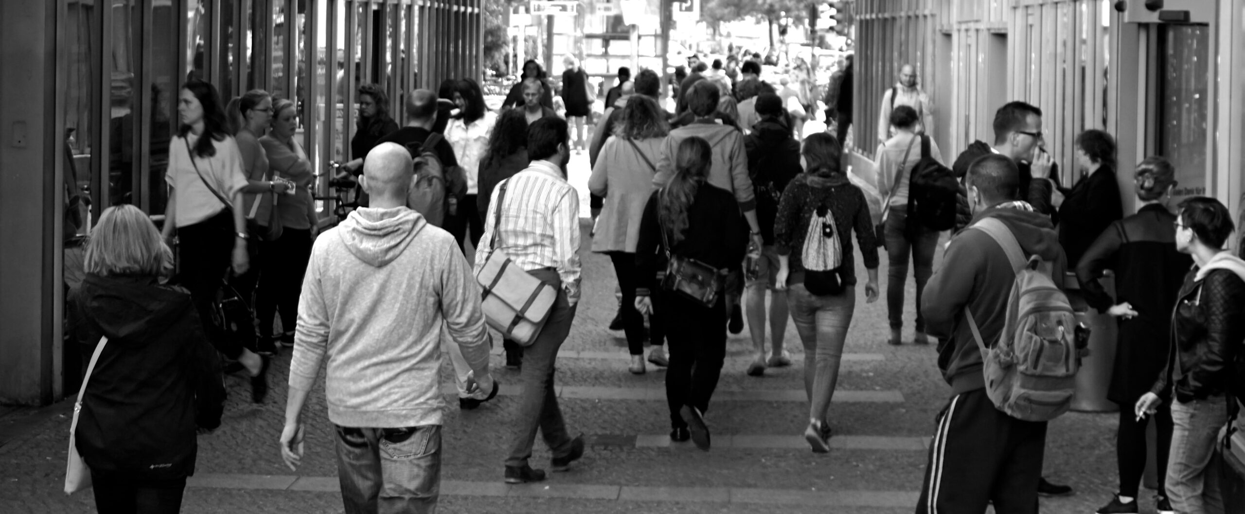 A crowd of people on a street, seen from behind.