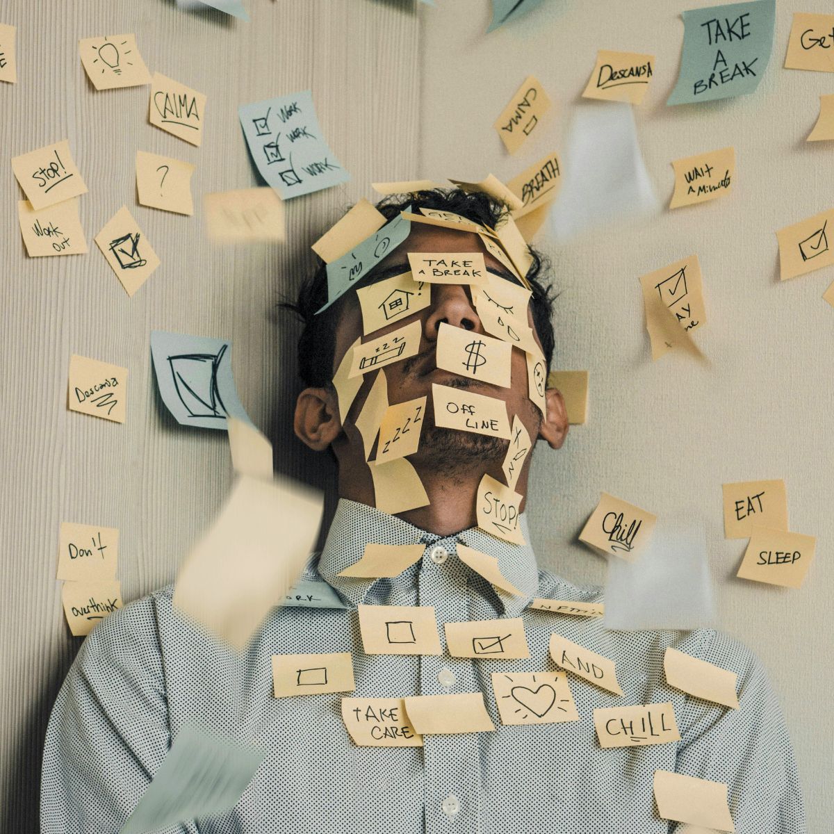 A man lying on the floor covered by sticky notes.