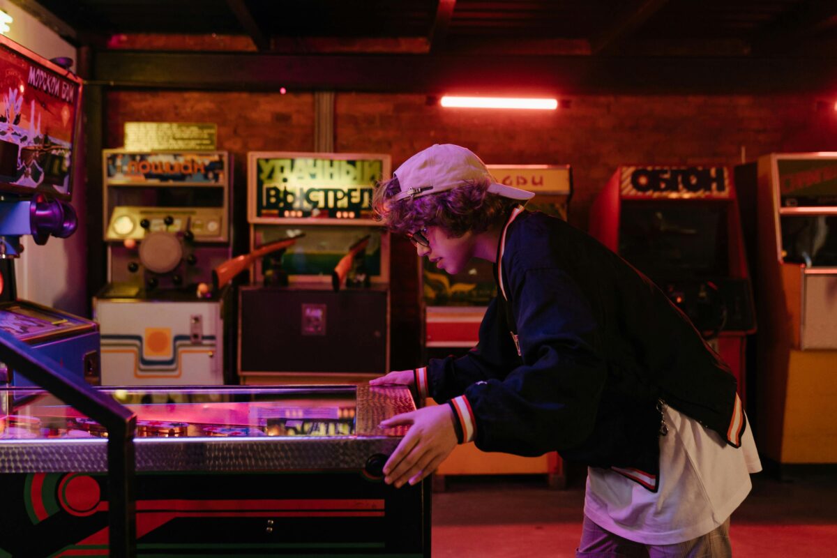 A young man playing a pinball machine