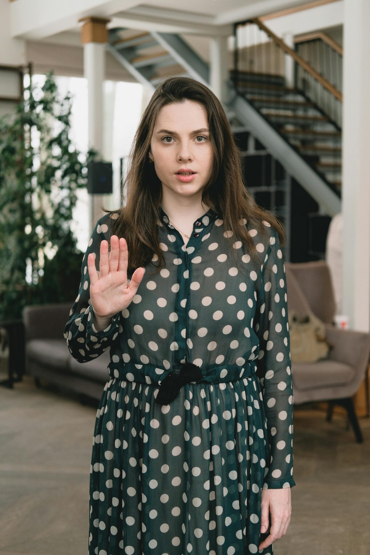 Woman standing in an office with her hand in the "stop" position.