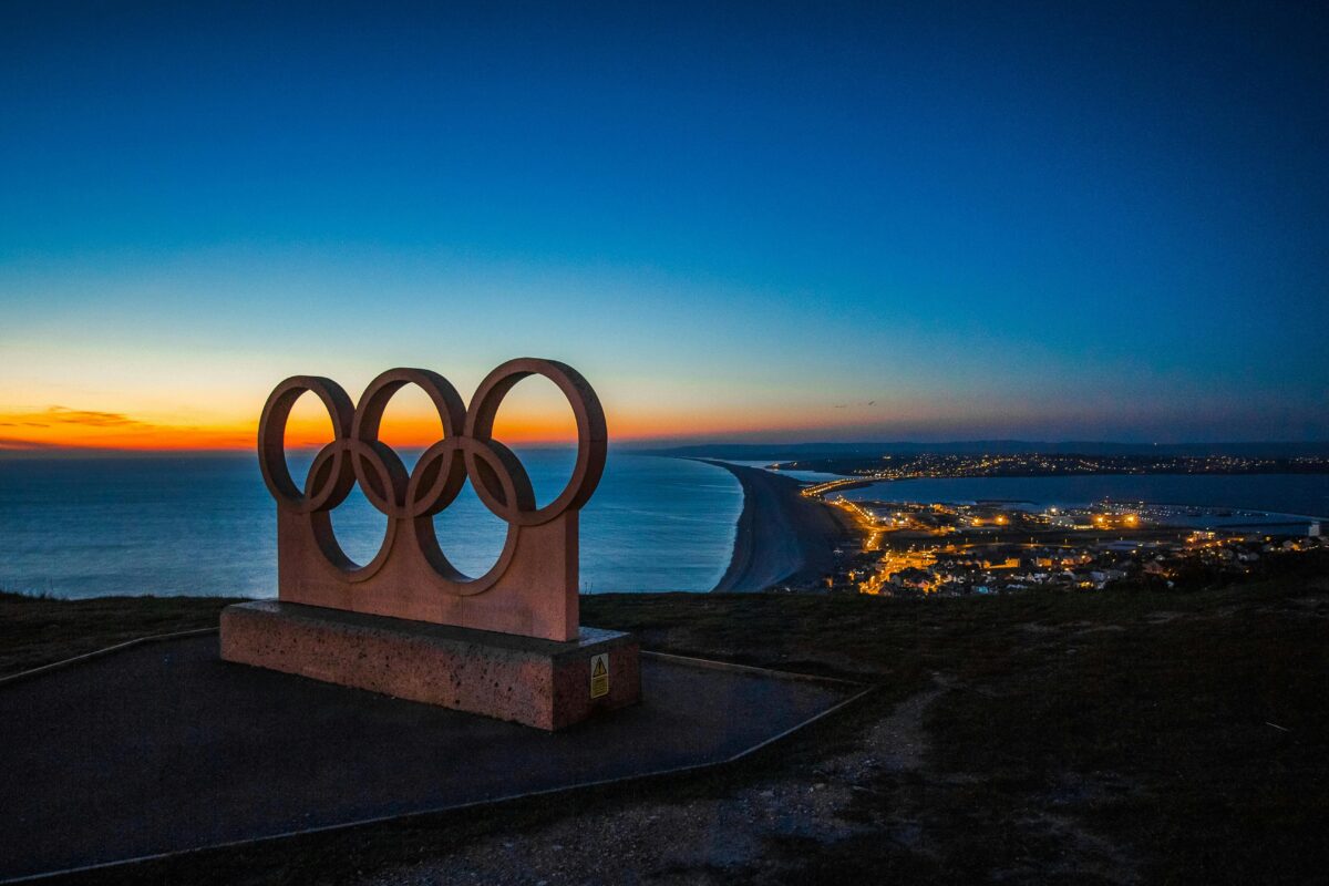 The Olympic Logo on a hilltop overlooking water.