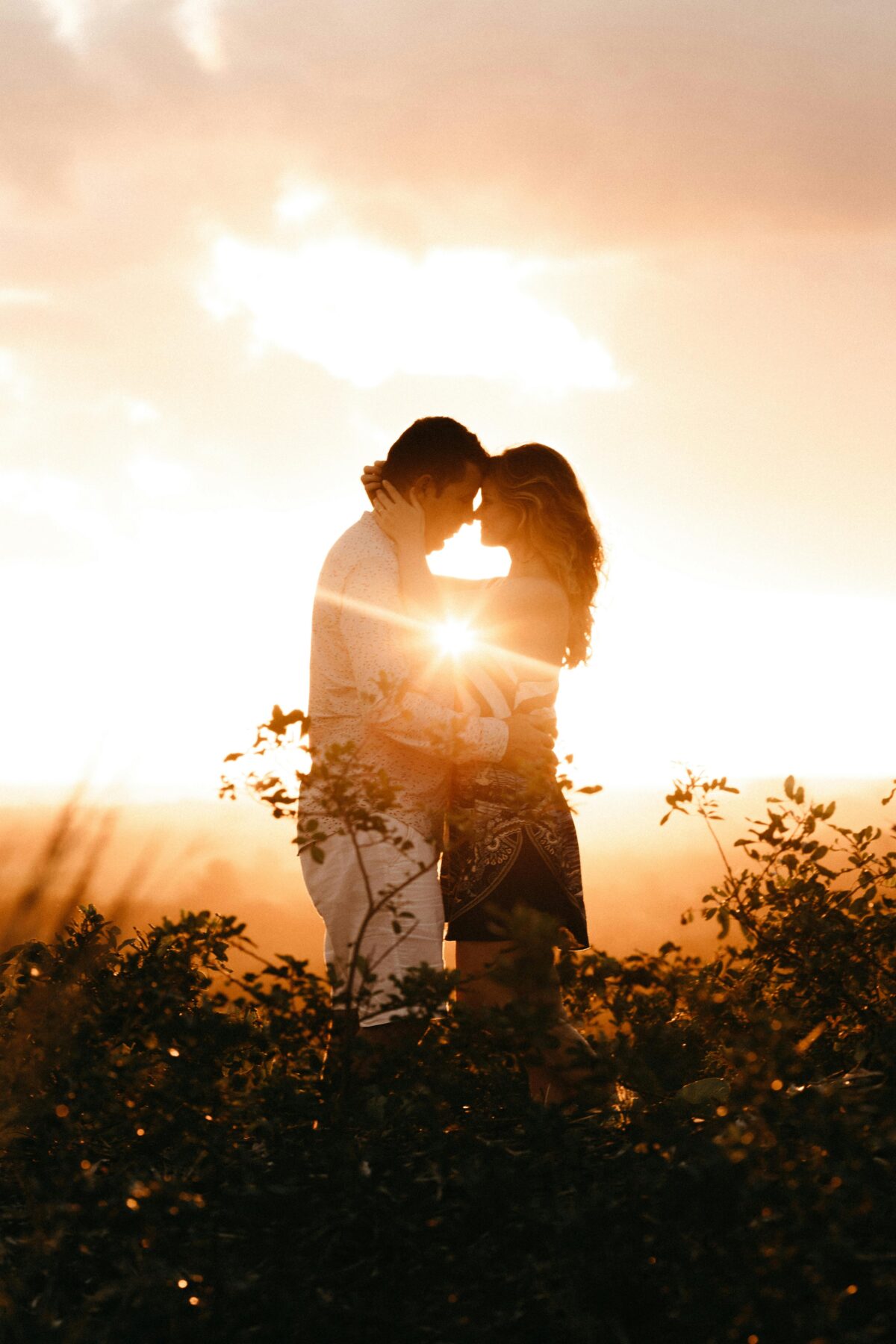 Man and Woman standing in a field and embracing in the sunlight.