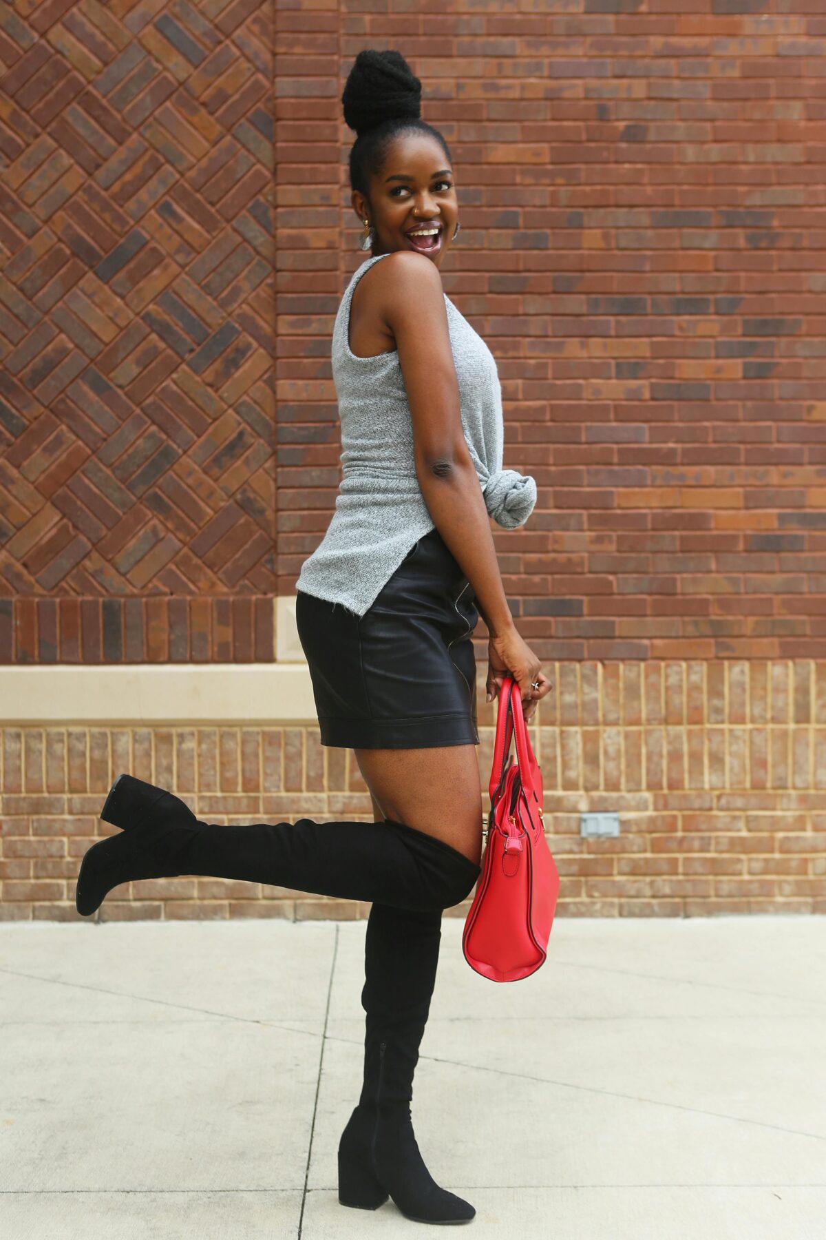 Woman wearing knee-high boots and carrying a red bag.