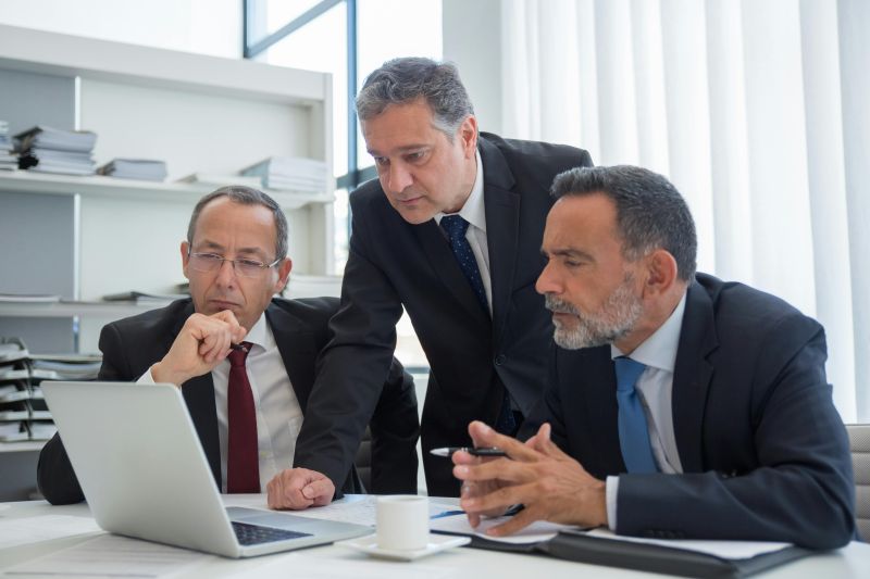 Three business people looking at a computer.