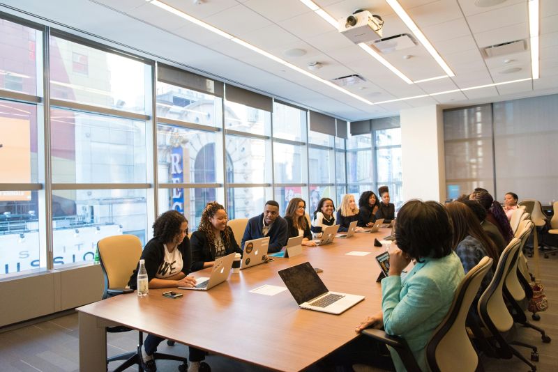 Large meeting of professionals around a boardroom table.