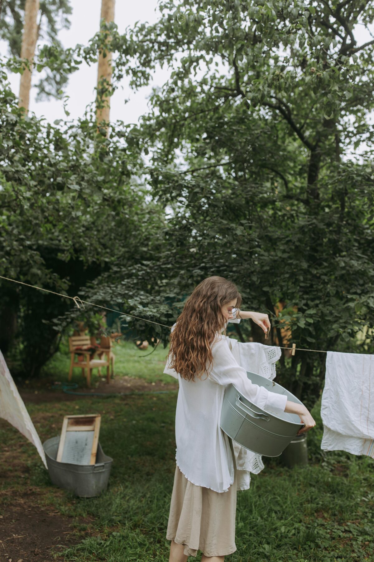 Woman holding a basket and hanging clothes on the line.