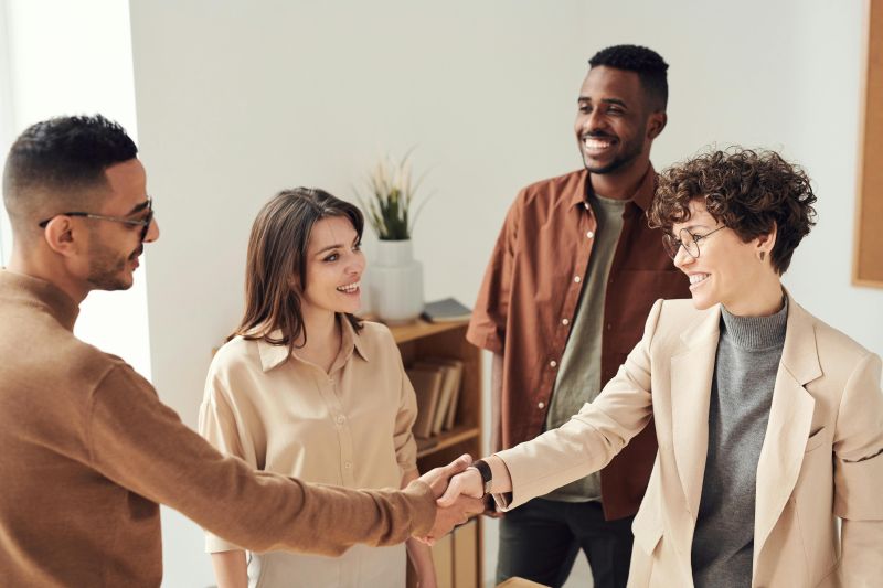 Group of young business people, two of whom are shaking hands.